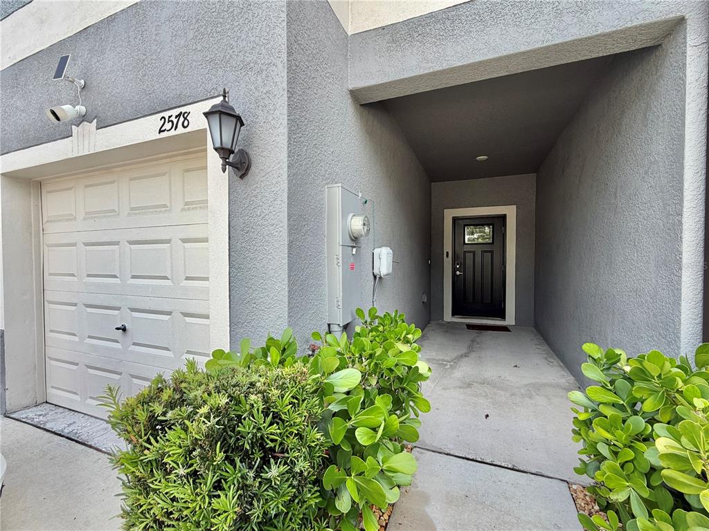 The exterior of a home features a garage, a recessed entryway, and green landscaping — 2578 CHARLAN COURT, HOLIDAY, FL