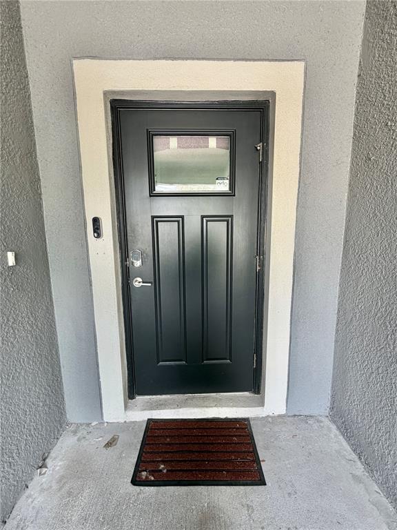A black front door with a window is set within a light-colored frame on a porch — 2578 CHARLAN COURT, HOLIDAY, FL