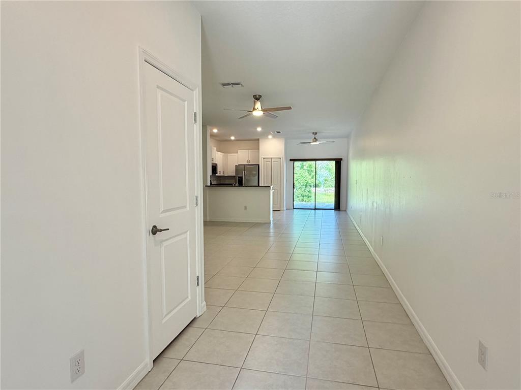 A view from a hallway looking into an open-concept kitchen and living area with tile floors — 2578 CHARLAN COURT, HOLIDAY, FL