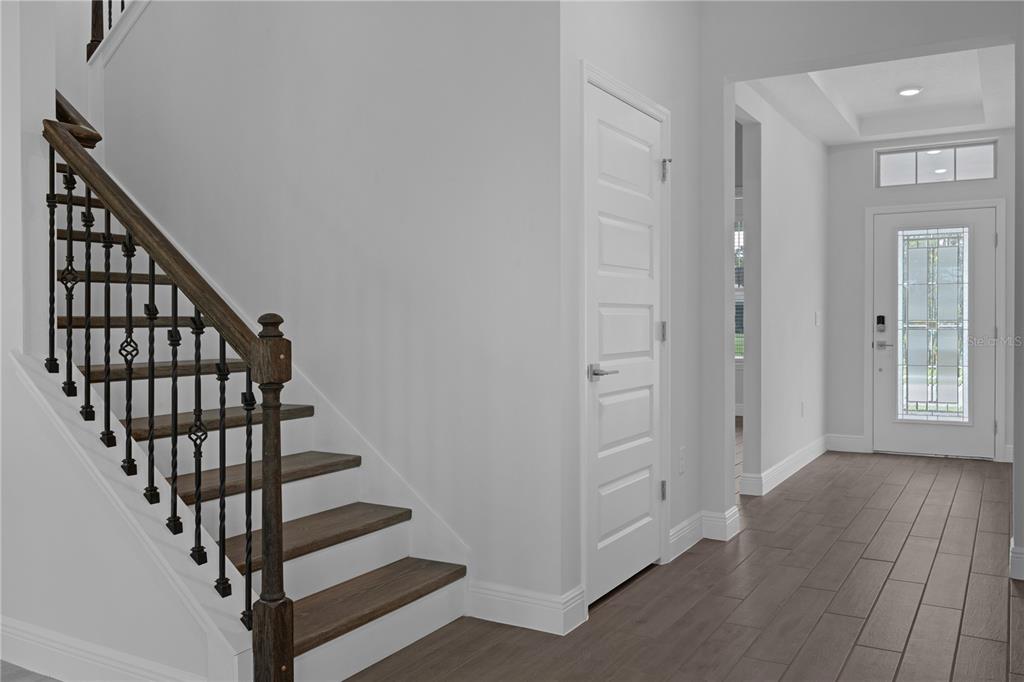 An interior view of a foyer featuring a wooden staircase with iron railings and tile flooring — 11821 SHINE VIEW LANE, WINTER GARDEN, FL