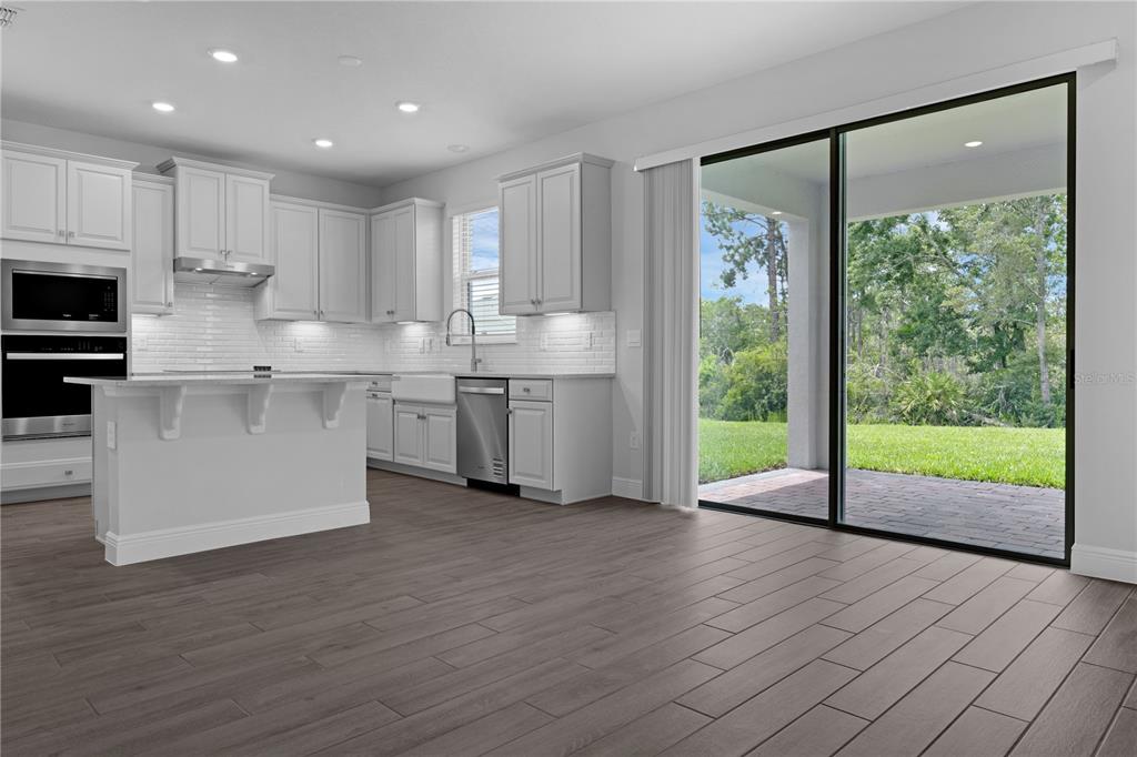 A modern kitchen with light gray cabinets, a center island, and sliding glass patio doors — 11821 SHINE VIEW LANE, WINTER GARDEN, FL