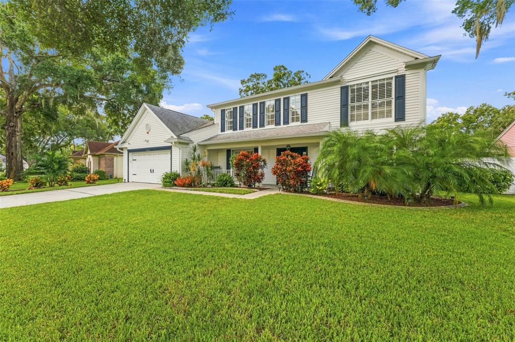 A two-story white house with dark shutters, a garage, and a large front lawn — 15622 INDIAN QUEEN DRIVE, ODESSA, FL