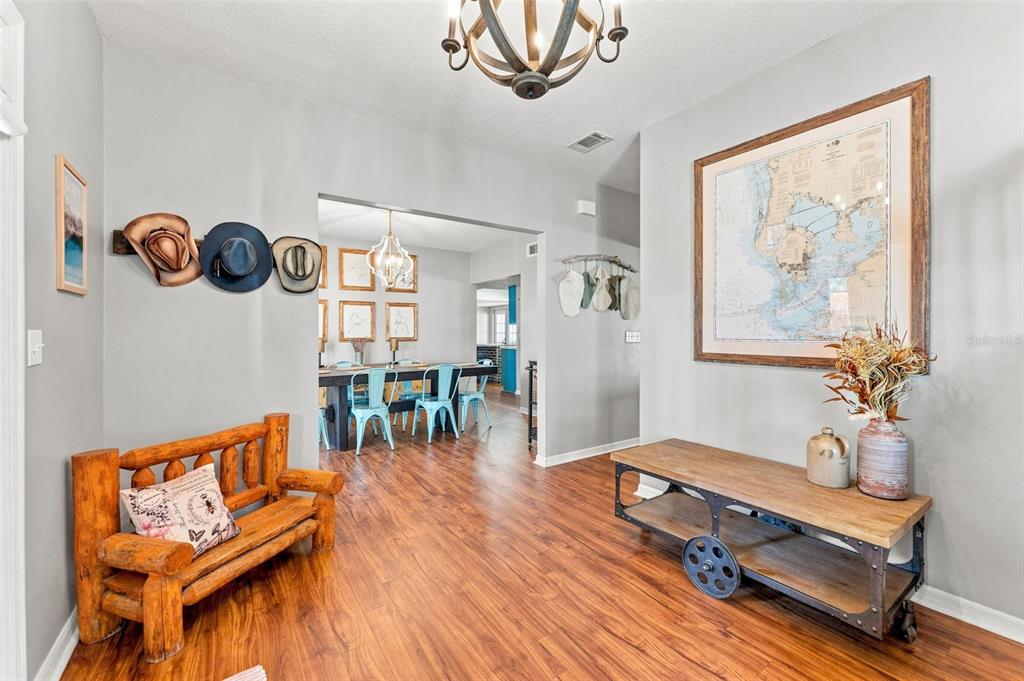 A foyer with wood flooring, a rustic log bench, a rolling cart, and wall-mounted hats — 15622 INDIAN QUEEN DRIVE, ODESSA, FL