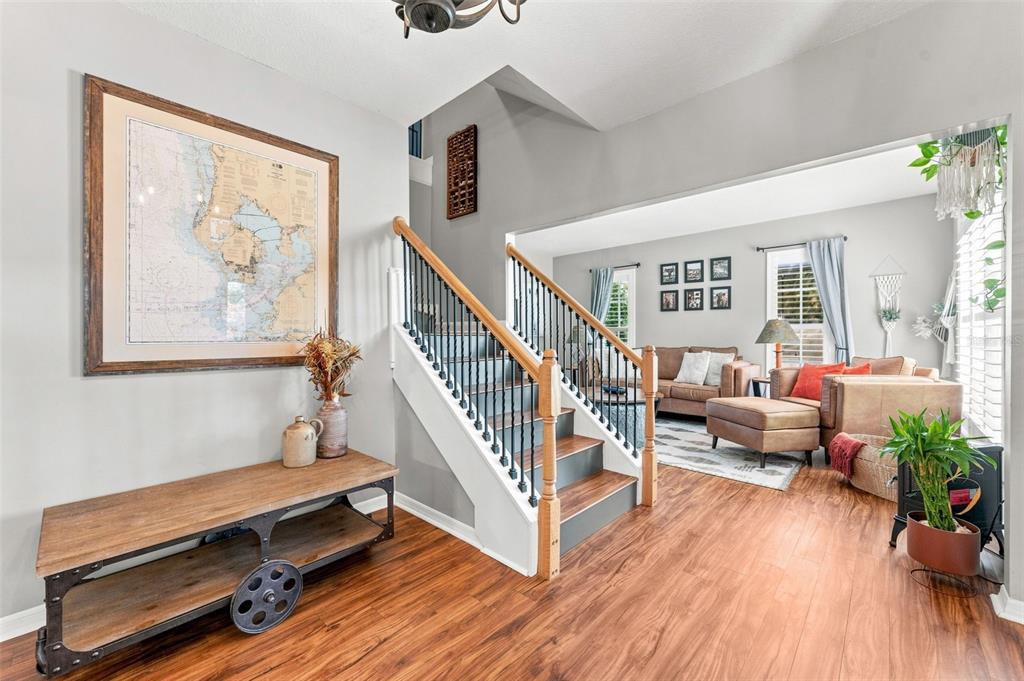 An entryway with a wooden console table, a staircase with iron railings, and a living room — 15622 INDIAN QUEEN DRIVE, ODESSA, FL