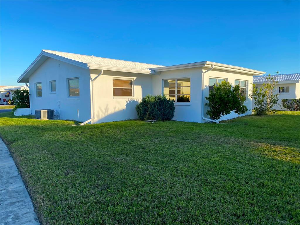 A white, single-story house with a lawn and a sidewalk under a clear blue sky — 10032 36TH STREET N, PINELLAS PARK, FL