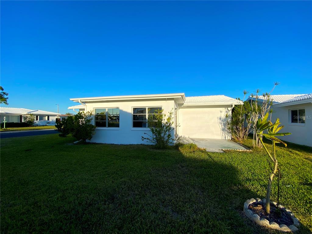The exterior of a white, single-story house features a flat roof and a concrete patio — 10032 36TH STREET N, PINELLAS PARK, FL