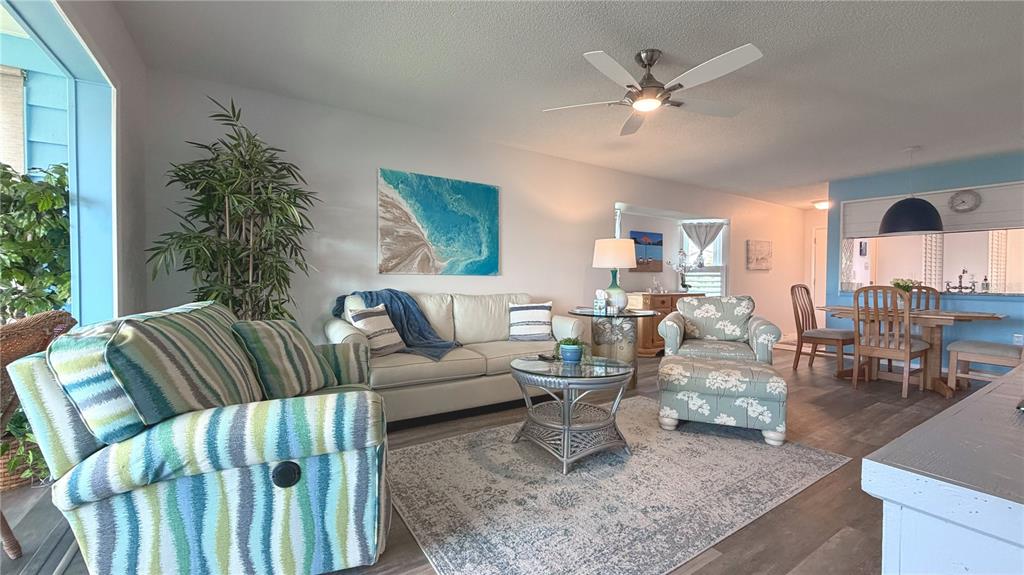 A living room features a striped armchair, a white sofa, and a floral patterned chair — 7163 28TH AVENUE W UNIT 7163, BRADENTON, FL