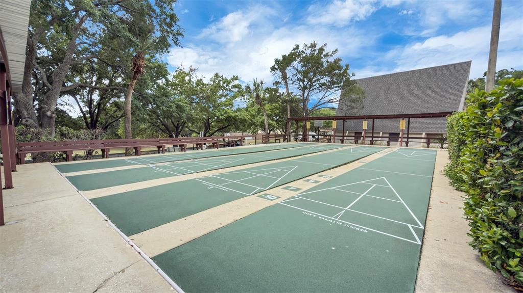 An outdoor shuffleboard court area features green playing surfaces, wooden benches, and surrounding trees — 10301 US HIGHWAY 27 UNIT 92, CLERMONT, FL