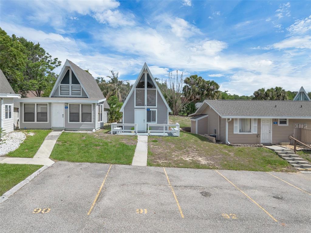 Three small houses with gray siding and a paved parking lot in the foreground — 10301 US HIGHWAY 27 UNIT 92, CLERMONT, FL