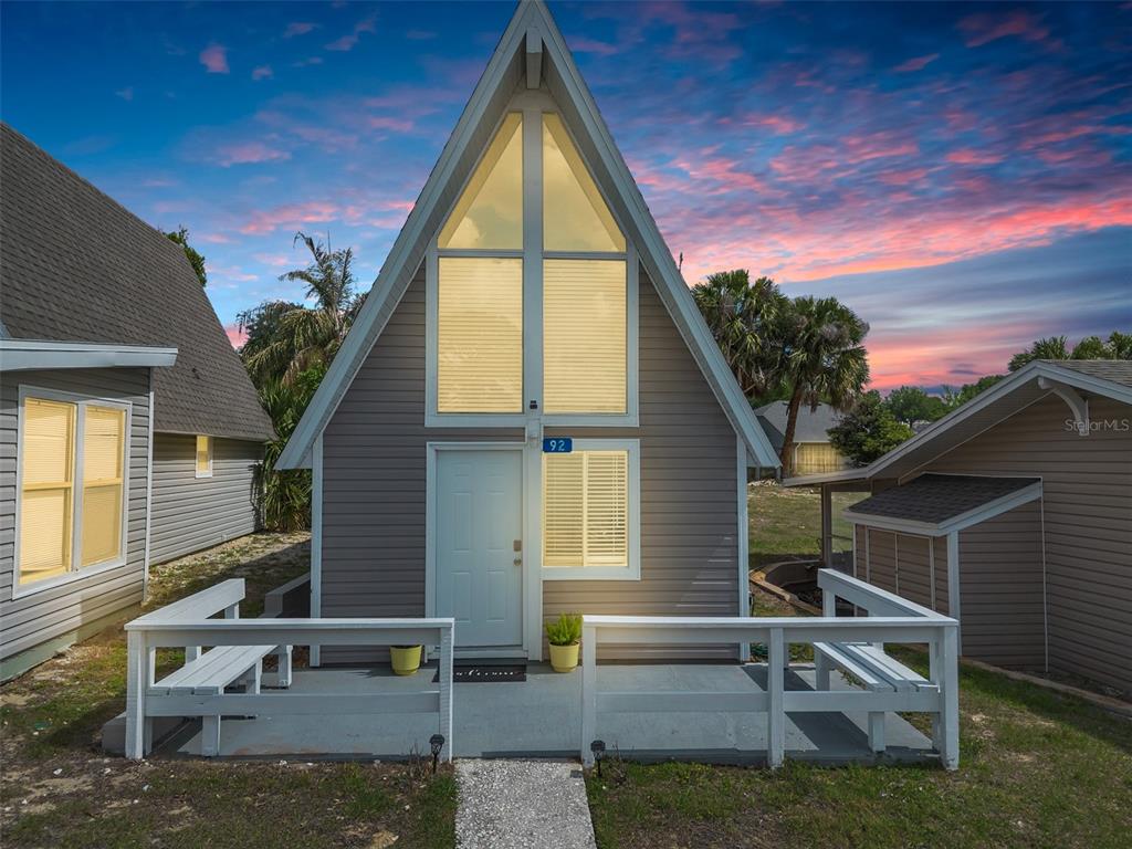 An A-frame house with gray siding, a white front door, and a wooden porch railing — 10301 US HIGHWAY 27 UNIT 92, CLERMONT, FL