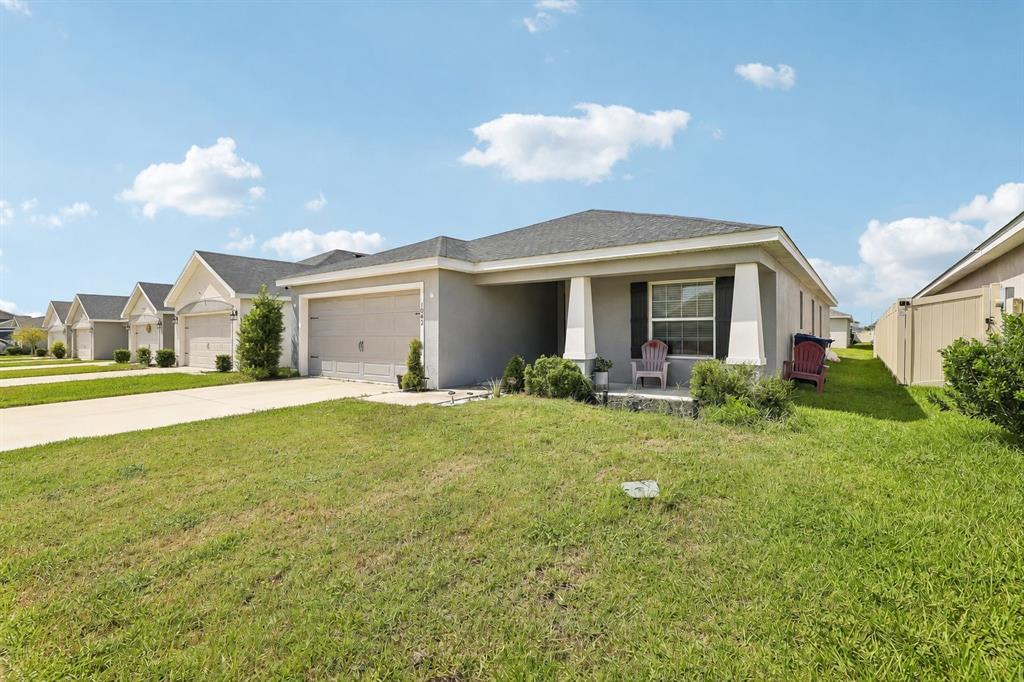 A single-story suburban house with a gray stucco exterior, a two-car garage, and a porch — 1042 CORSO DR, WINTER HAVEN, FL