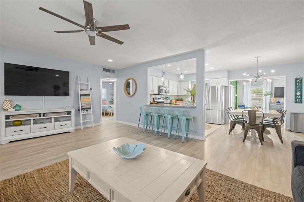 A bright open-concept living room features a kitchen island with stools and a dining area — 1405 TEMPLE STREET, CLEARWATER, FL