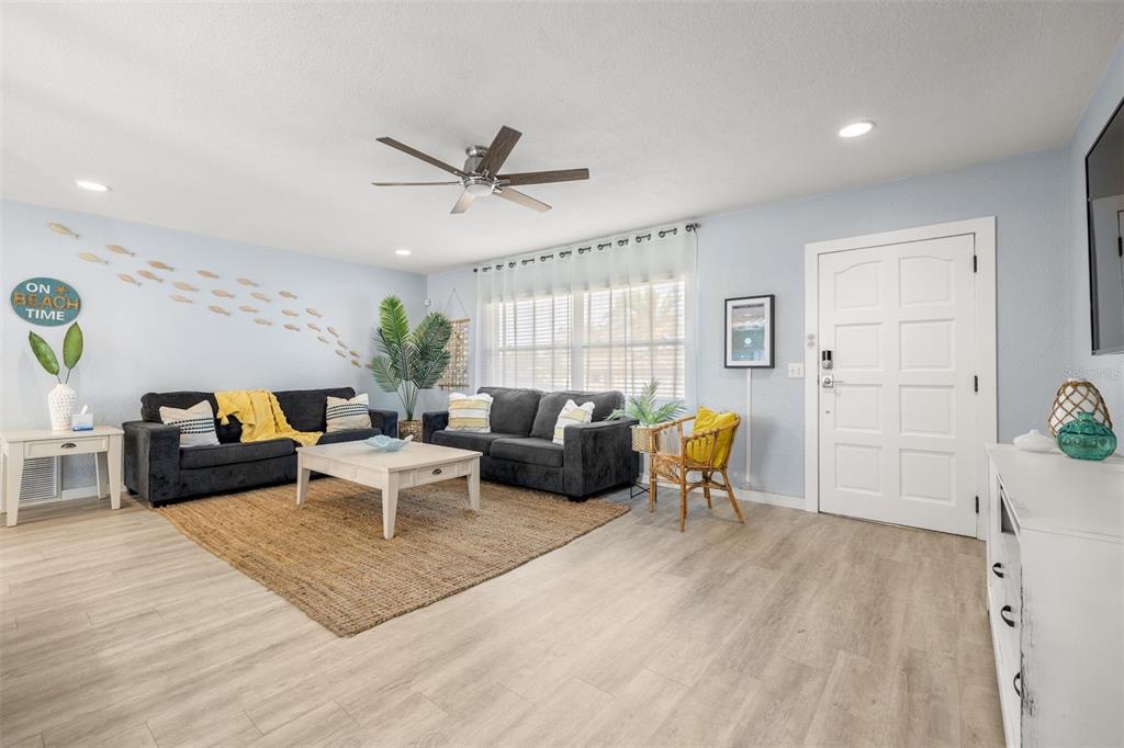 A living room features two dark sofas, a coffee table, and light wood-look flooring — 1405 TEMPLE STREET, CLEARWATER, FL