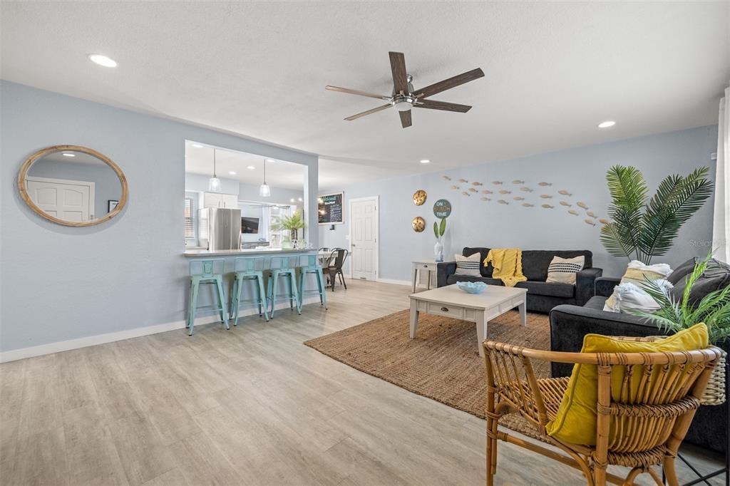 A living room features light blue walls, wood-look flooring, a ceiling fan, and a breakfast bar — 1405 TEMPLE STREET, CLEARWATER, FL