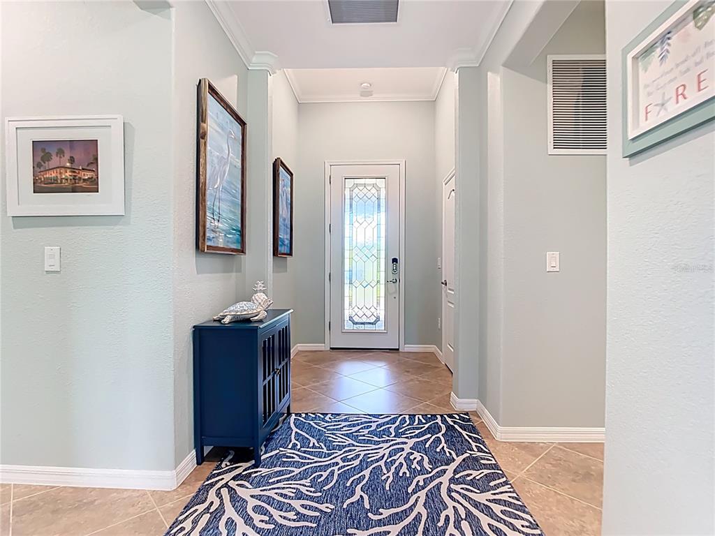 A bright entryway features light blue walls, tile flooring, a blue cabinet, and a front door — 12297 CANAVESE LANE, VENICE, FL