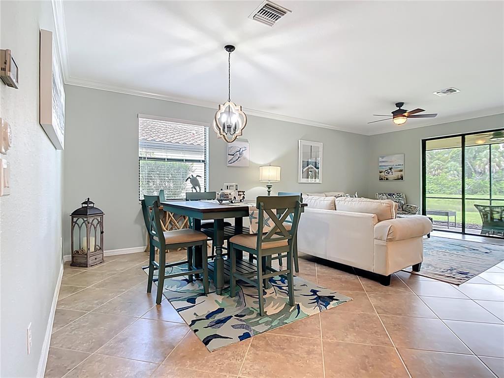 A dining area with a wooden table and chairs sits adjacent to a living room — 12297 CANAVESE LANE, VENICE, FL