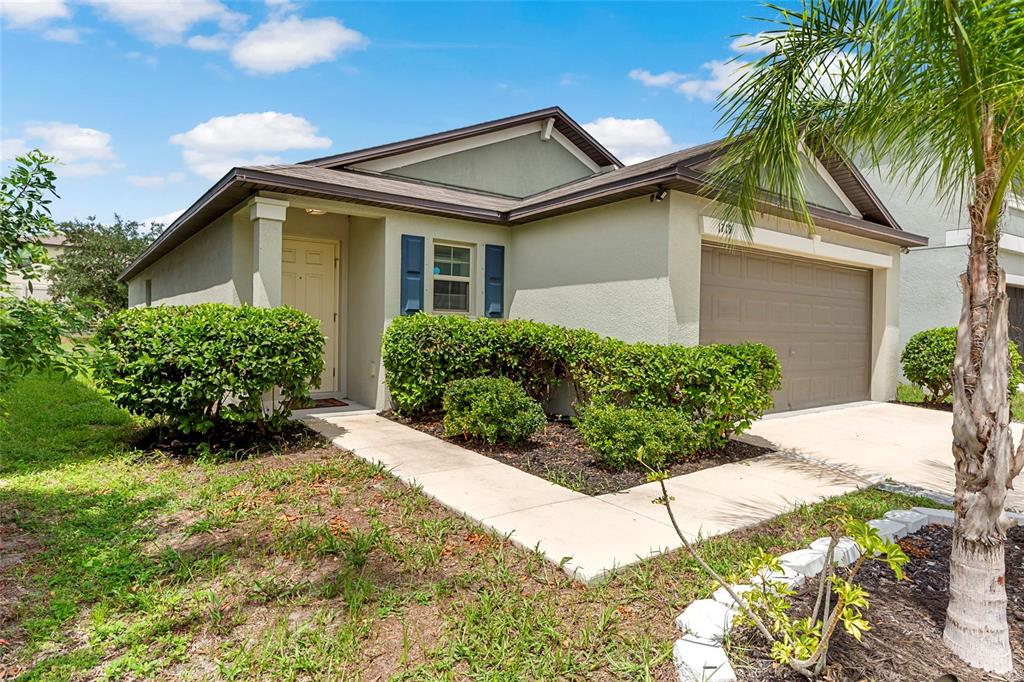 A single-story house with a beige stucco exterior, a brown garage door, and front landscaping — 1719 FRED IVES STREET, RUSKIN, FL