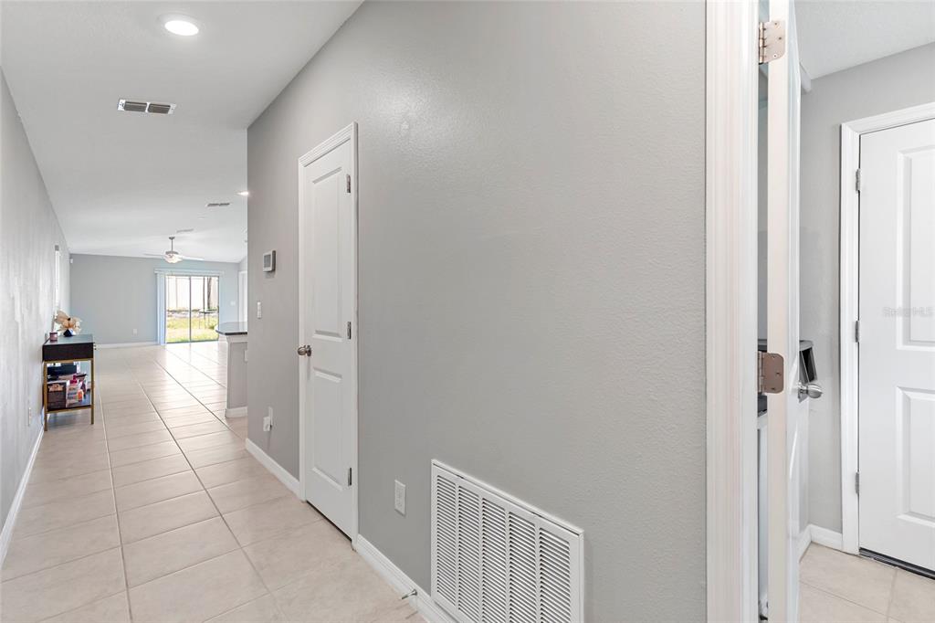 A hallway with light tile flooring leads toward a living area with a sliding door — 1719 FRED IVES STREET, RUSKIN, FL