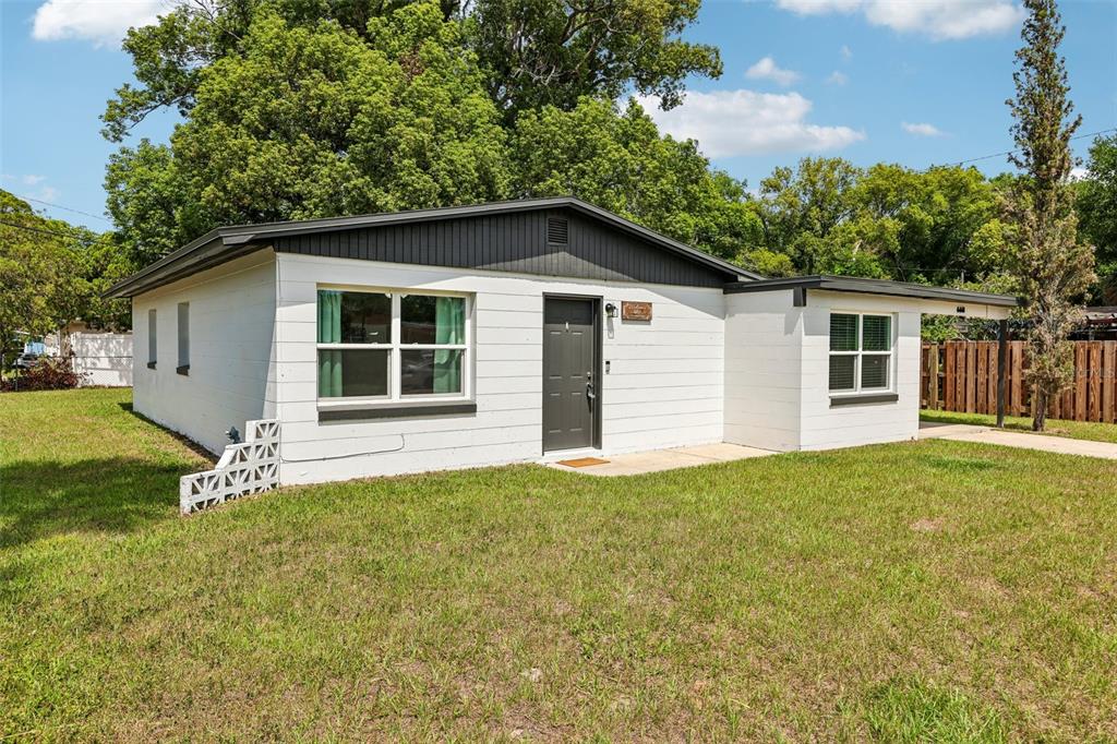 A single-story white house with a dark gray roof and door sits on a lawn — 668 BARBUDA WAY, ALTAMONTE SPRINGS, FL