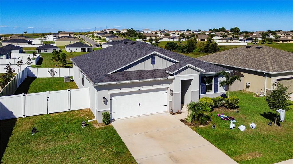 An aerial view of a single-story suburban house with a two-car garage and fenced yard — 1404 GERANIUM DRIVE, MASCOTTE, FL