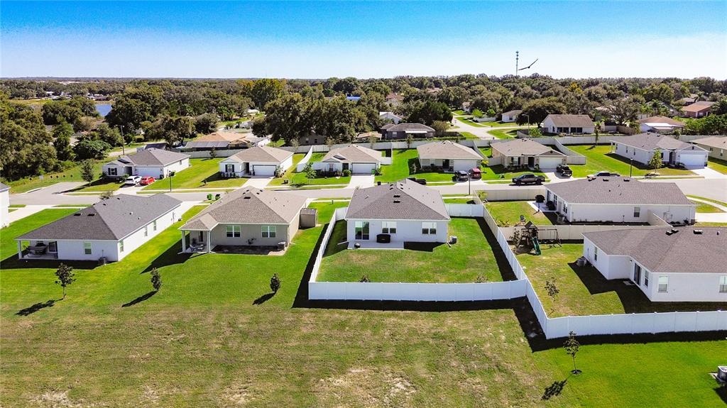 An aerial view shows several suburban houses with fenced backyards and green lawns — 1404 GERANIUM DRIVE, MASCOTTE, FL