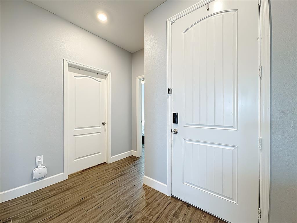 An entryway features light gray walls, wood-look tile flooring, and two white interior doors — 1404 GERANIUM DRIVE, MASCOTTE, FL