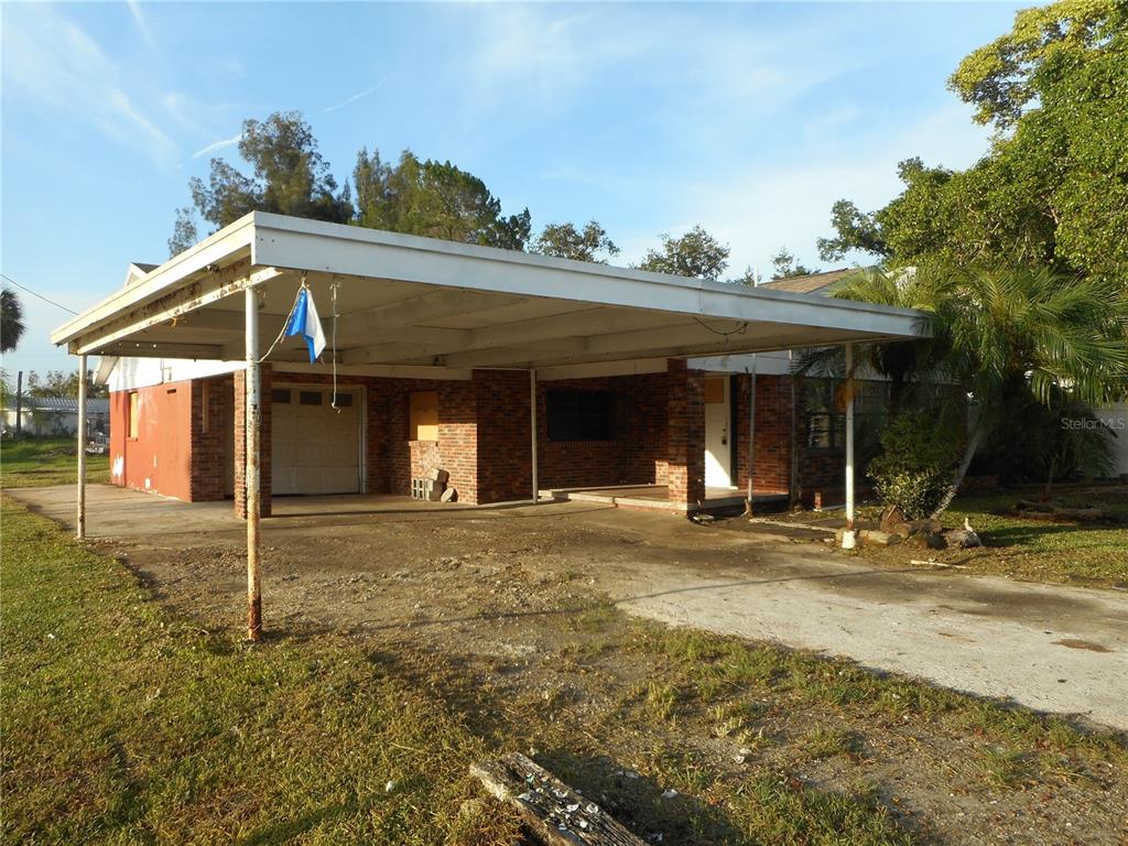 A single-story brick house features a large attached carport and a concrete driveway — 609 1ST AVENUE NW, RUSKIN, FL