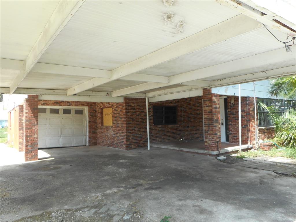 A brick house exterior features a large concrete carport and a single-car garage — 609 1ST AVENUE NW, RUSKIN, FL