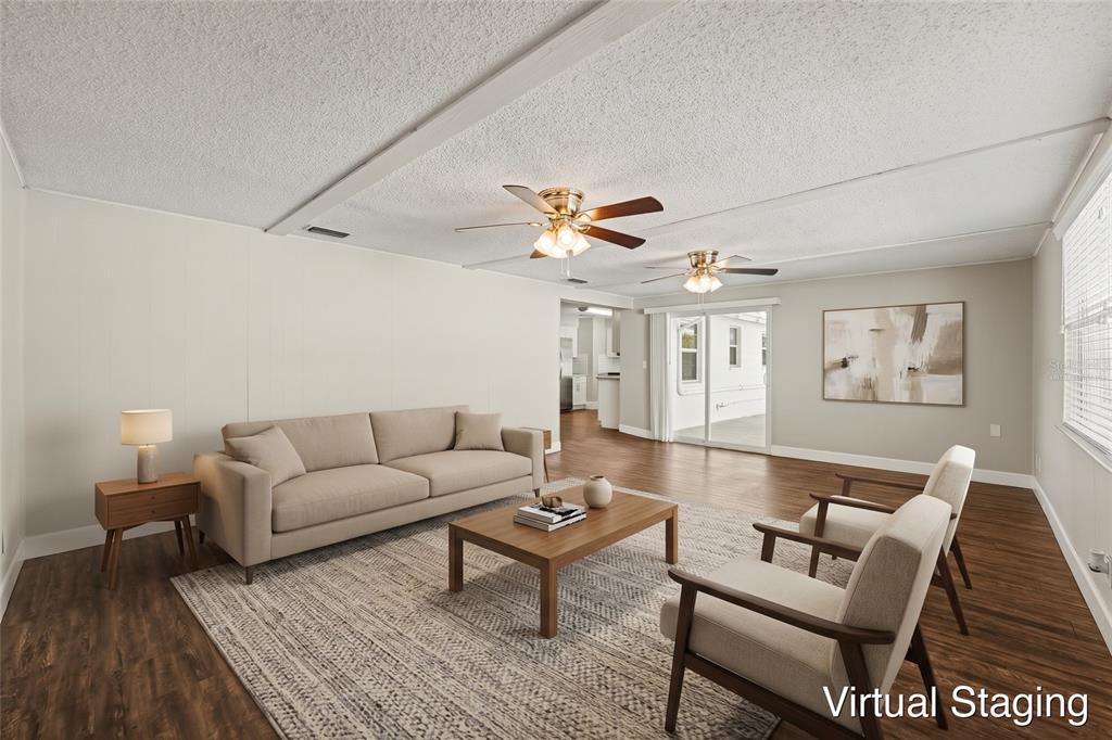 An open-concept living area features wood-look flooring, light-colored walls, and a view into the kitchen — 1615 SENECA AVENUE, LAKELAND, FL