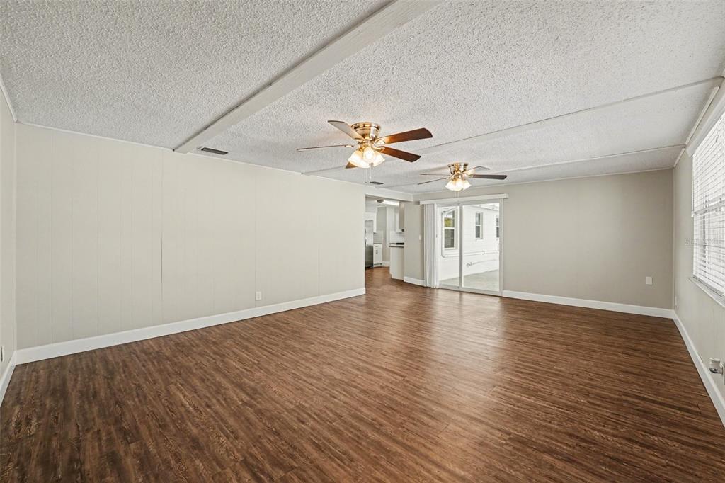 An interior view of a room with wood-look flooring, light-colored walls, and multiple doorways — 1615 SENECA AVENUE, LAKELAND, FL