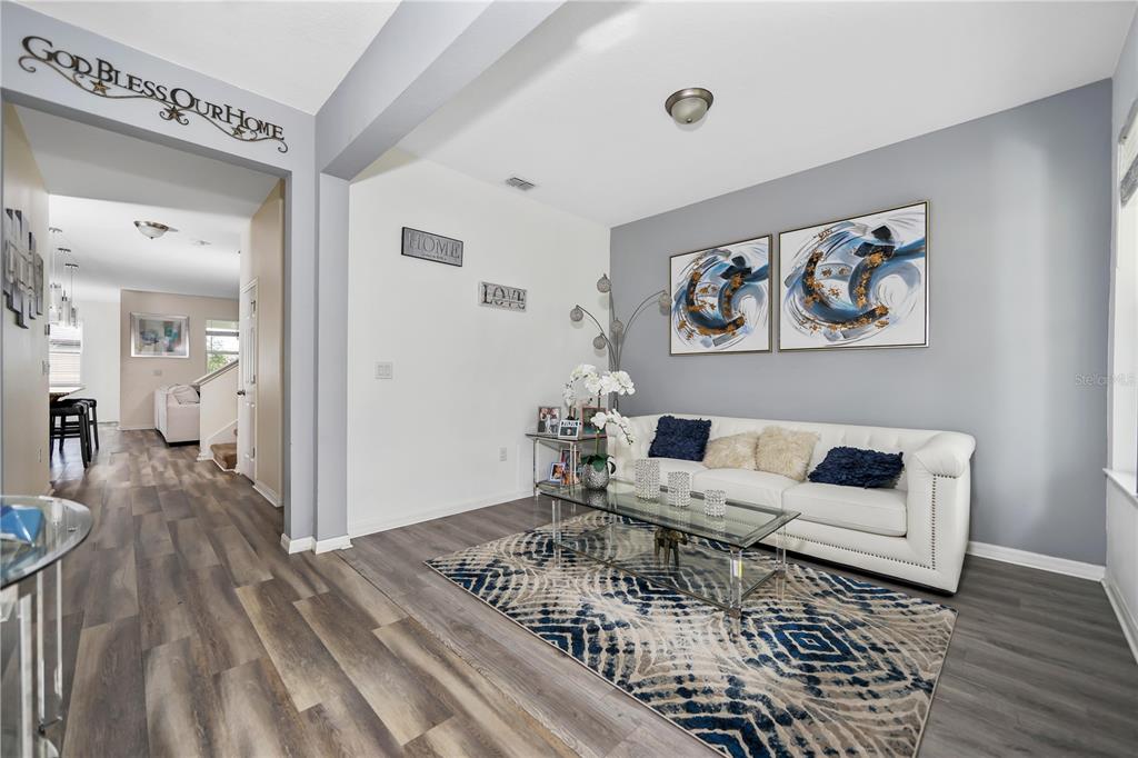 A living room features a white sofa, a glass coffee table, and a patterned area rug — 3107 STONEGATE DRIVE, OCOEE, FL