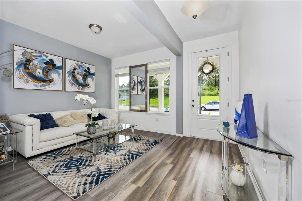 A living room features a white sofa, patterned rug, glass coffee table, and front door — 3107 STONEGATE DRIVE, OCOEE, FL