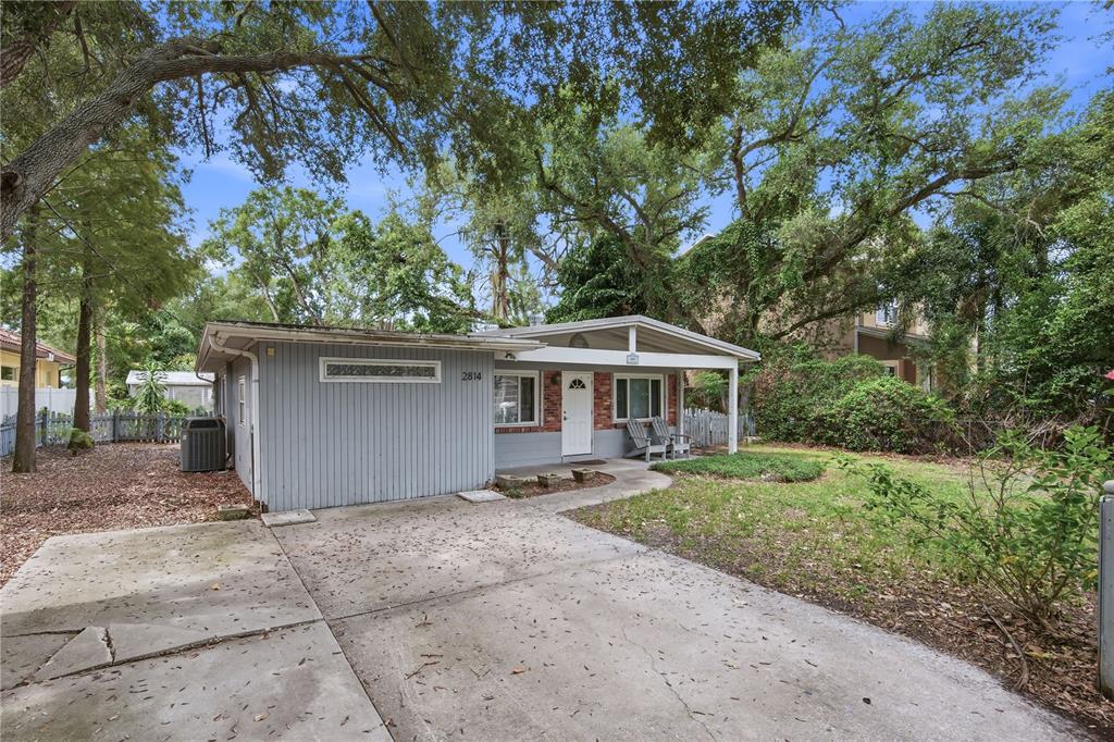 A kitchen with wood cabinets and stainless steel appliances overlooks a hallway with wood flooring — 2814 W PRICE AVENUE, TAMPA, FL