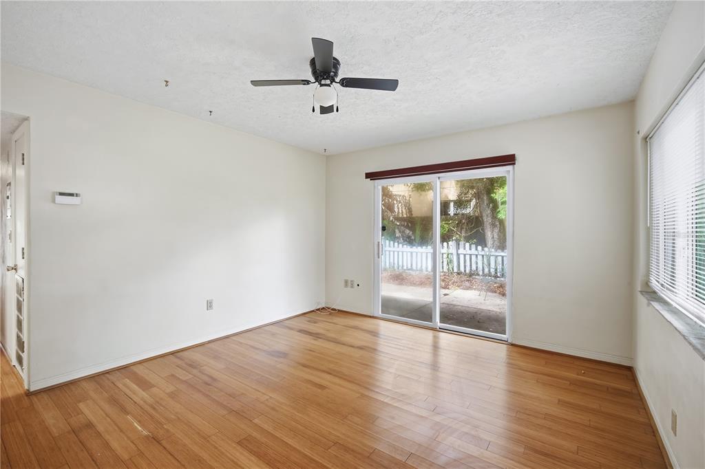 An empty room features light wood flooring, a ceiling fan, sliding glass doors, and windows — 2814 W PRICE AVENUE, TAMPA, FL