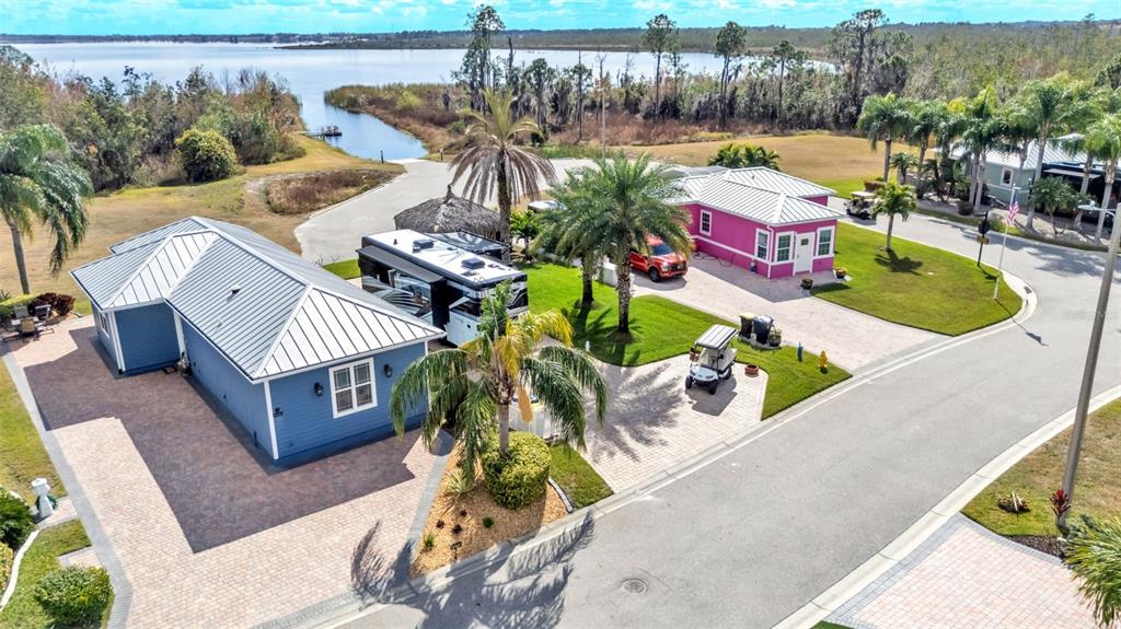 An aerial view shows two colorful houses with metal roofs, a parked RV, and palm trees — 3272 FISH HAWK DRIVE, POLK CITY, FL