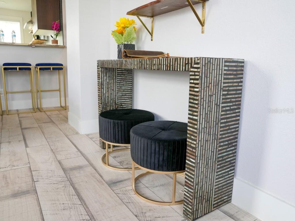 A console table with a mosaic finish sits in a room with two black ottomans — 121-123 N HOLLYWOOD AVENUE, DAYTONA BEACH, FL
