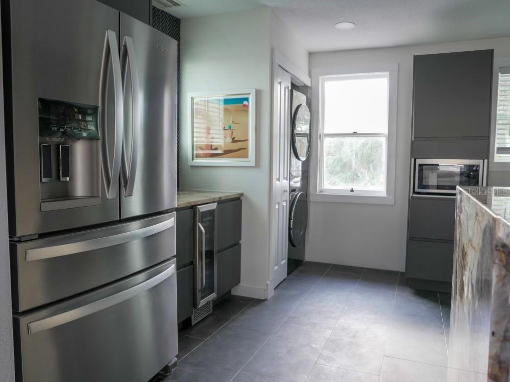 A kitchen featuring stainless steel appliances, dark gray cabinets, and a laundry closet with stacked units — 121-123 N HOLLYWOOD AVENUE, DAYTONA BEACH, FL