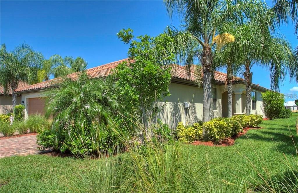 A single-story house with a tiled roof, palm trees, and a brick driveway — 6627 CANDLESTICK DRIVE, BRADENTON, FL