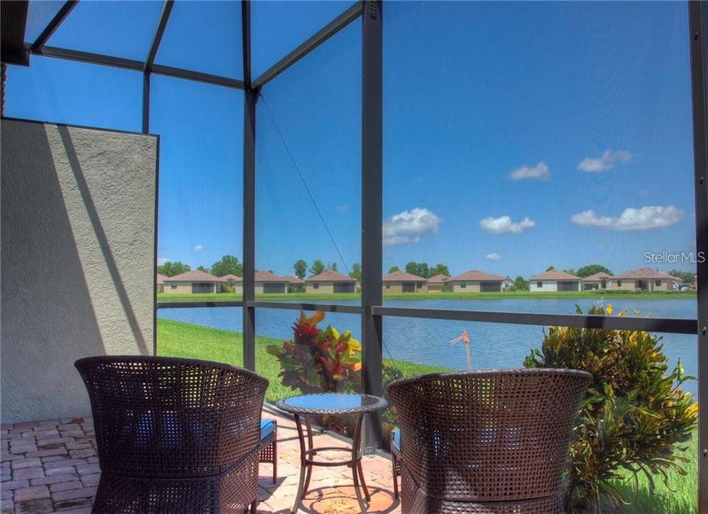 A screened-in patio features two wicker chairs and a small table overlooking a lake — 6627 CANDLESTICK DRIVE, BRADENTON, FL