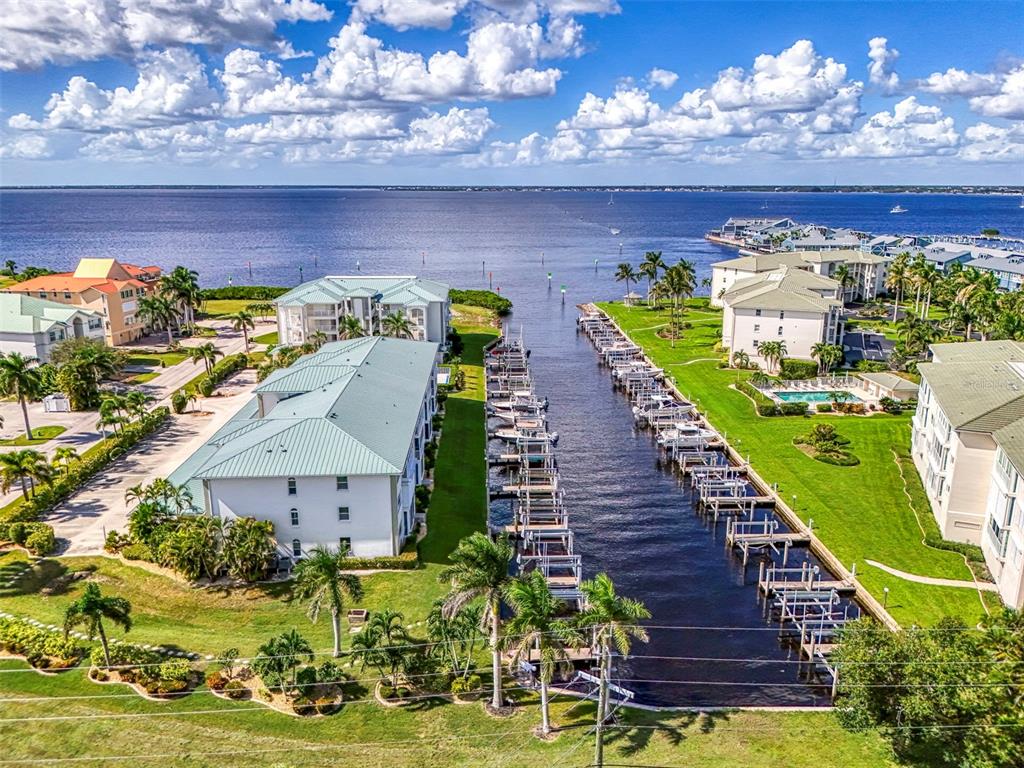 An aerial view shows two multi-story apartment buildings with a swimming pool and boat docks — 130 BREAKERS COURT UNIT 221, PUNTA GORDA, FL