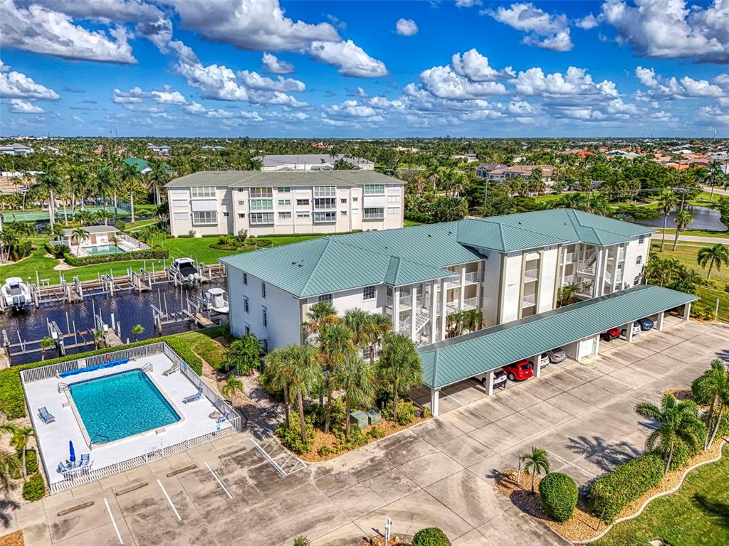 An aerial view shows a canal with boat slips between residential buildings and palm trees — 130 BREAKERS COURT UNIT 221, PUNTA GORDA, FL