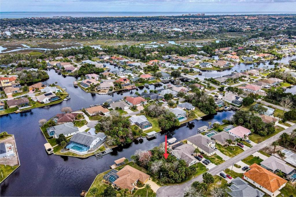 An aerial view shows a vacant, wooded residential lot situated along a canal in Florida — 16 CRANDON COURT, PALM COAST, FL