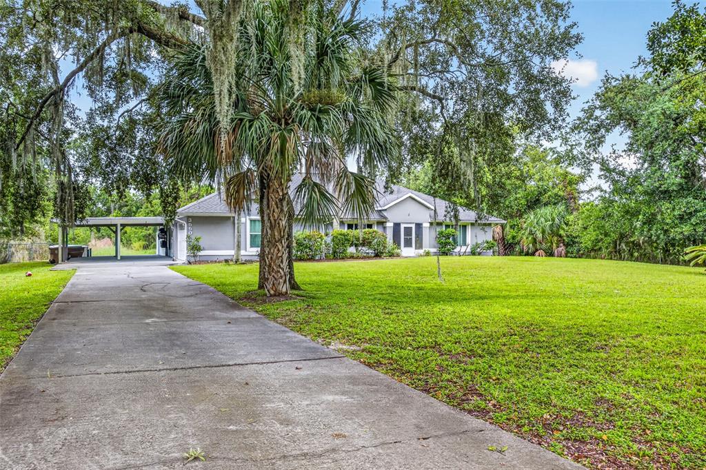 A single-story house with a concrete driveway, a carport, and a large front lawn — 3550 OBERRY ROAD, KISSIMMEE, FL