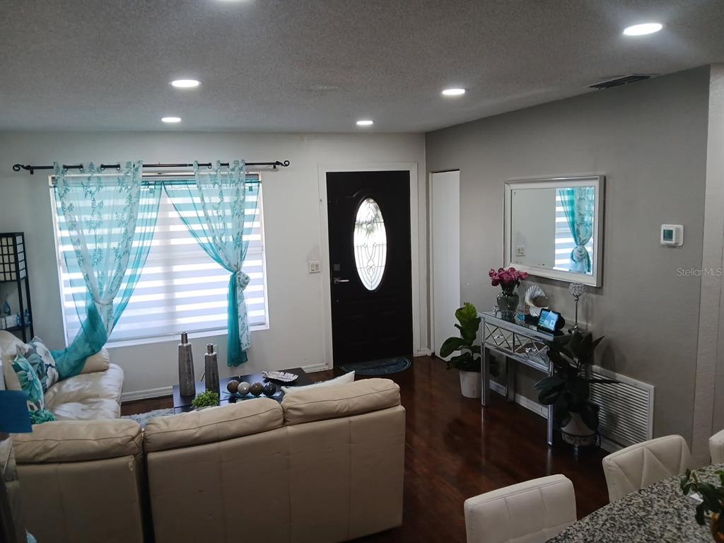 A living room with a beige sectional sofa, dark wood floors, and a black front door — 14342 SE 45TH COURT, SUMMERFIELD, FL