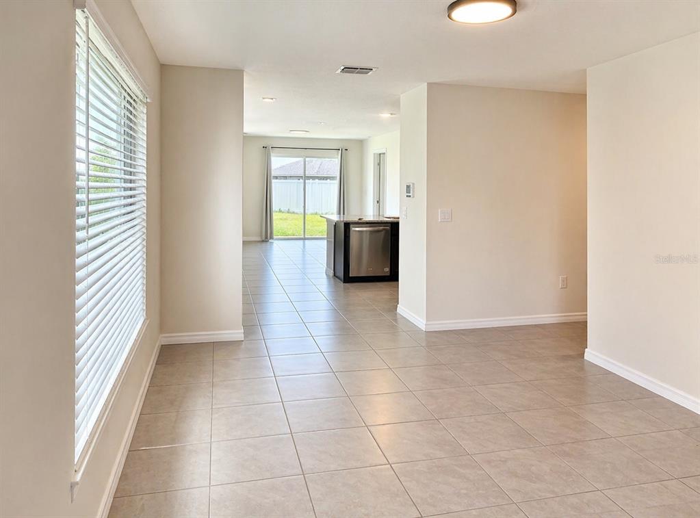 A tiled dining area leads to a kitchen with stainless steel appliances and sliding doors — 16511 MOSAIC OAR DRIVE, WIMAUMA, FL