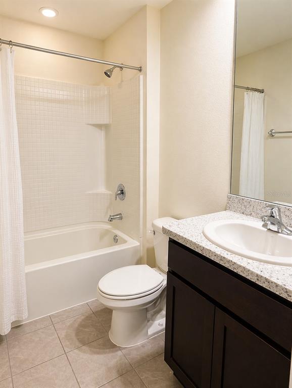 A bathroom features a white tub-shower combo, a toilet, and a dark vanity with granite — 16511 MOSAIC OAR DRIVE, WIMAUMA, FL