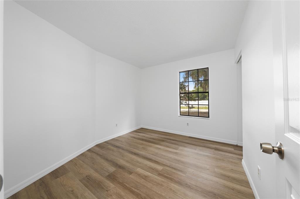 An empty bedroom with white walls, wood-look flooring, and a single window — 401 HAGER DRIVE, OCOEE, FL