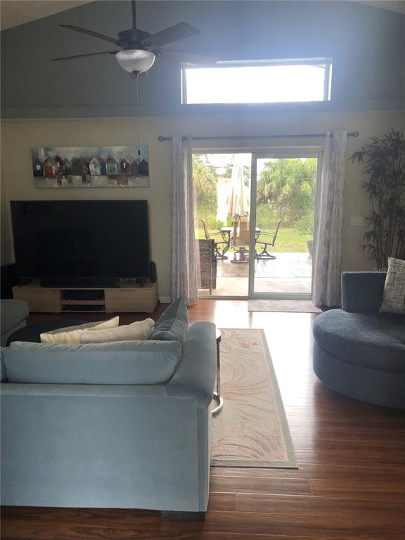 A living room features a vaulted ceiling, sliding glass doors, and a large television — 10125 PEOPLES LOOP, PORT RICHEY, FL