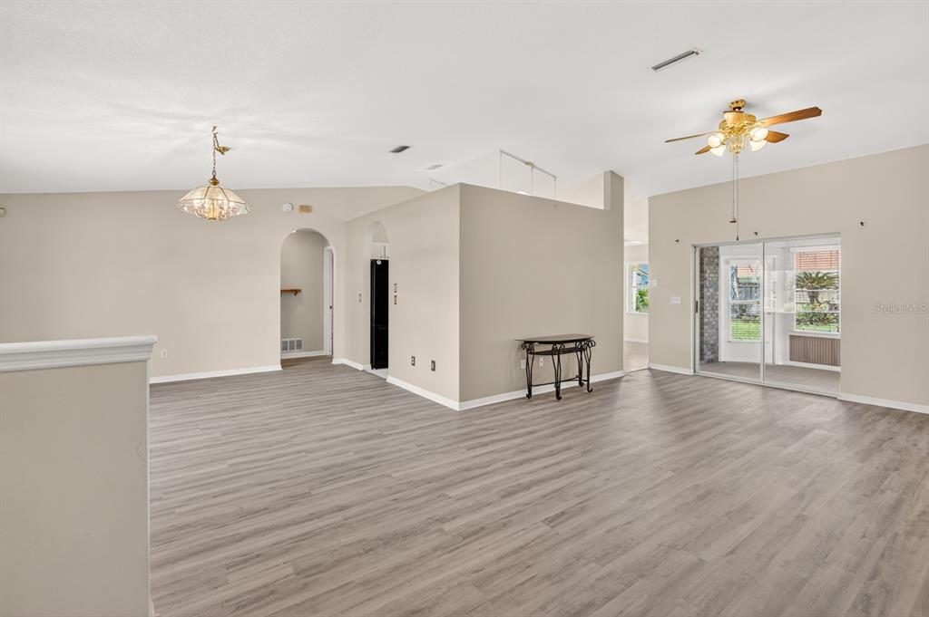 An open-concept living area features light-colored walls, wood-look flooring, and a sliding glass door — 153 WELLSTONE DRIVE, PALM COAST, FL