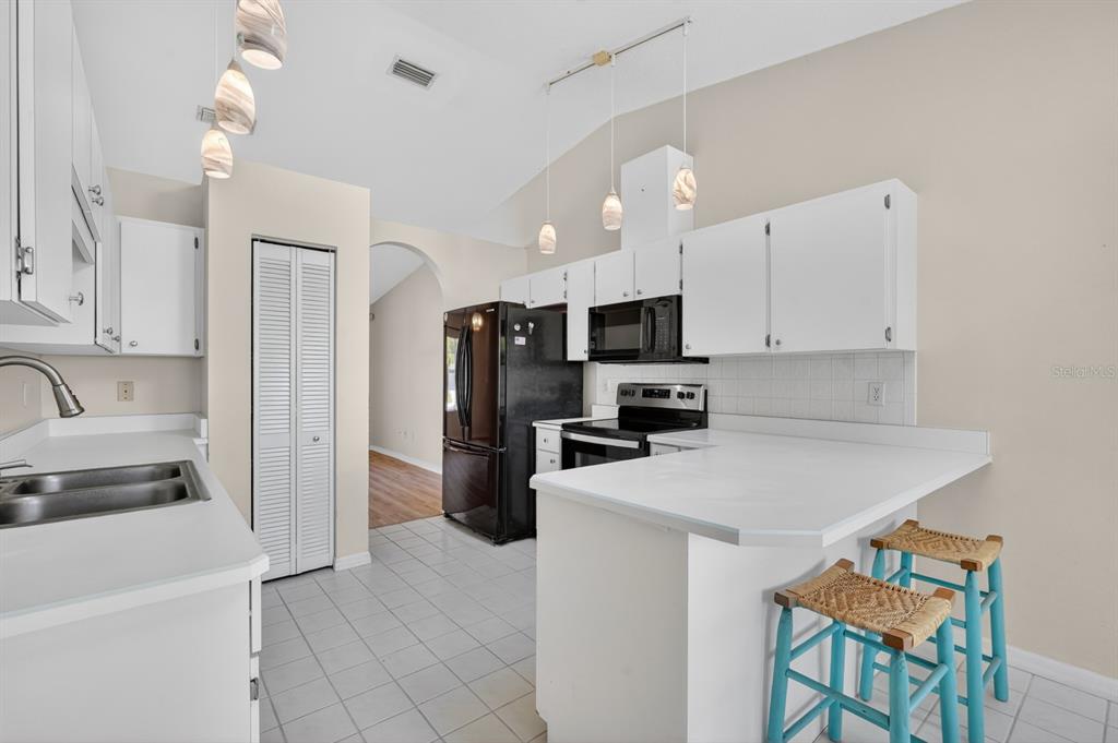 A kitchen with white cabinets, white countertops, a black refrigerator, and a tiled floor — 153 WELLSTONE DRIVE, PALM COAST, FL